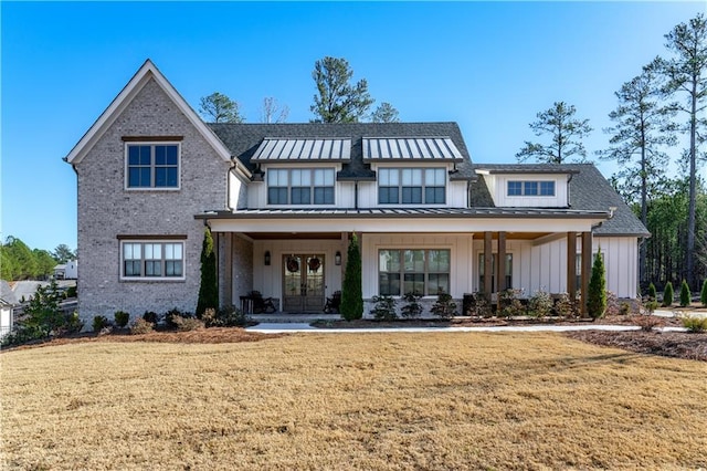 modern farmhouse style home featuring french doors, board and batten siding, a front yard, a standing seam roof, and metal roof