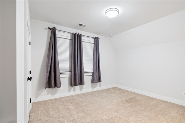 spare room featuring baseboards, visible vents, vaulted ceiling, and carpet flooring