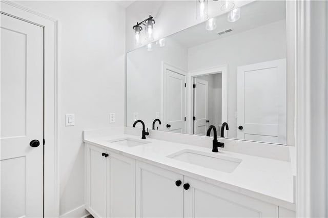 bathroom with visible vents, a sink, and double vanity