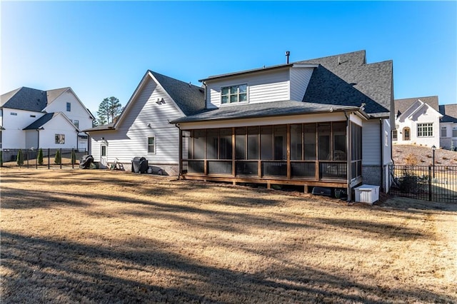 rear view of house featuring a sunroom, a shingled roof, fence, and a yard