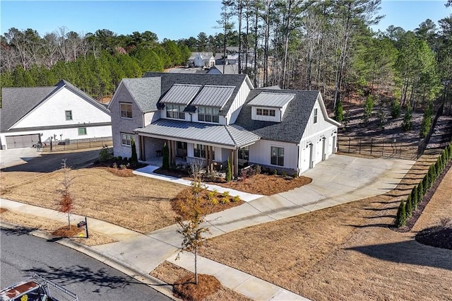 modern inspired farmhouse with covered porch, fence, metal roof, and a standing seam roof