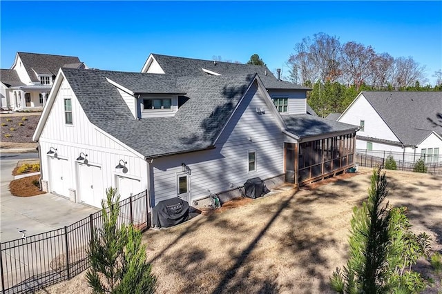 back of house featuring a shingled roof, concrete driveway, a sunroom, an attached garage, and fence