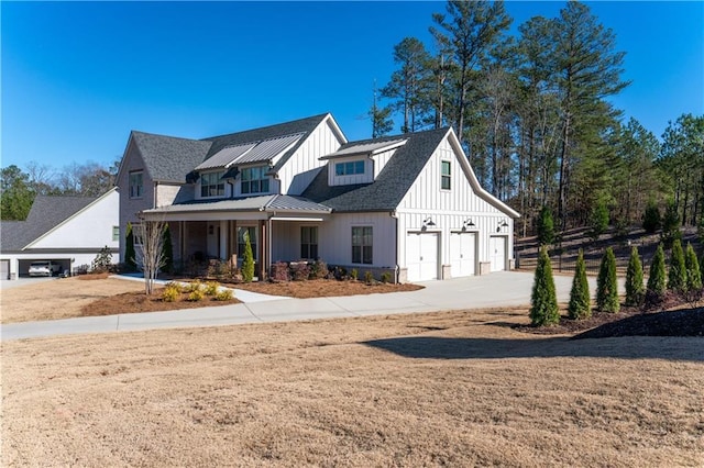 modern farmhouse featuring board and batten siding, concrete driveway, metal roof, and a standing seam roof