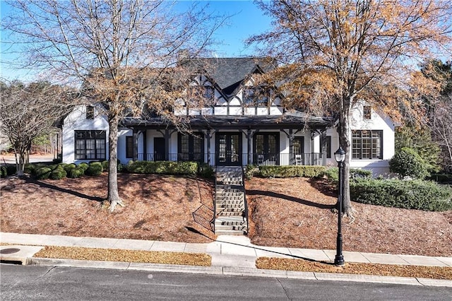 view of front of house with french doors, stairway, and stucco siding