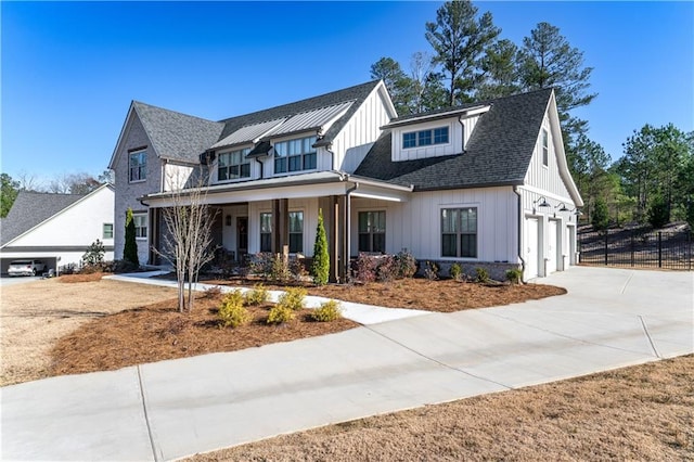 modern farmhouse featuring concrete driveway, an attached garage, covered porch, fence, and board and batten siding