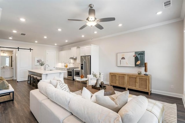 living room with ceiling fan, dark hardwood / wood-style floors, and a barn door