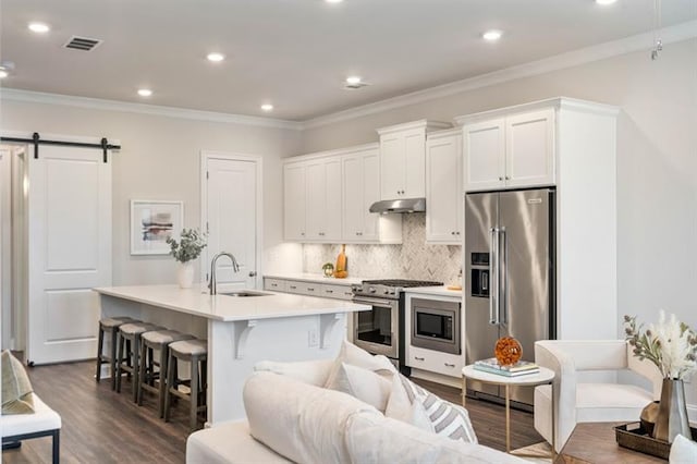 kitchen featuring high end appliances, dark hardwood / wood-style floors, sink, and a barn door