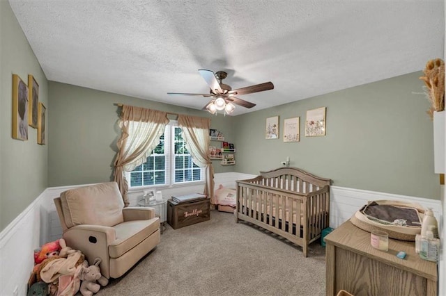 586 Old Bushmill Rd, Bremen, GA 30110 - bedroom featuring wainscoting, a textured ceiling, carpet flooring, a crib, and a ceiling fan