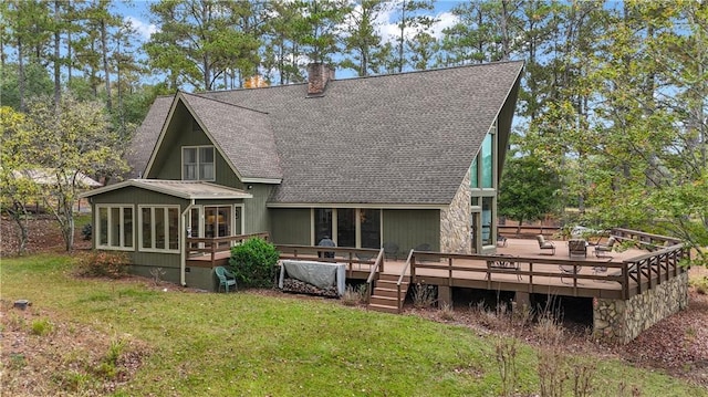 back of property featuring a wooden deck, a sunroom, and a lawn