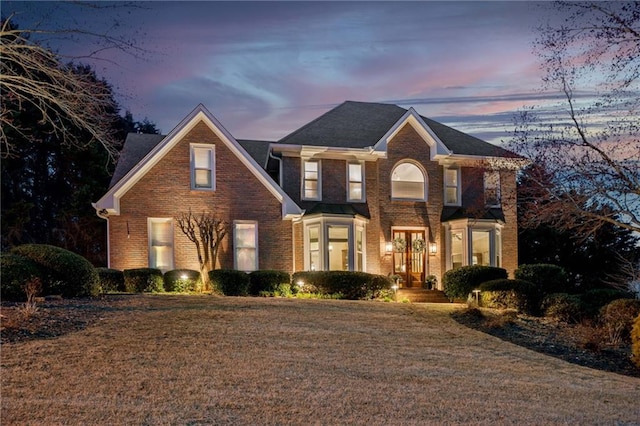 view of front of property featuring brick siding and a lawn