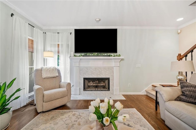 living area featuring a premium fireplace, stairway, wood finished floors, and ornamental molding