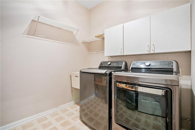 laundry area featuring washing machine and clothes dryer, cabinet space, baseboards, and light floors