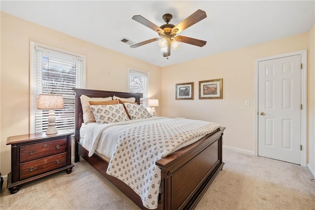 bedroom with visible vents, light colored carpet, baseboards, and ceiling fan