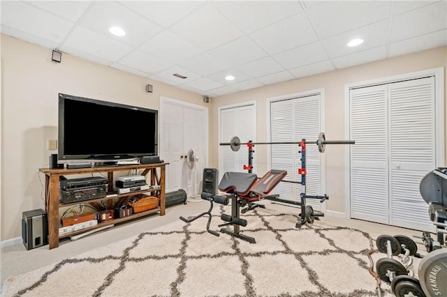 exercise room with a paneled ceiling, baseboards, and carpet