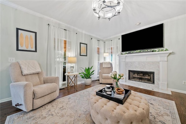 living room featuring wood finished floors, baseboards, a premium fireplace, an inviting chandelier, and ornamental molding