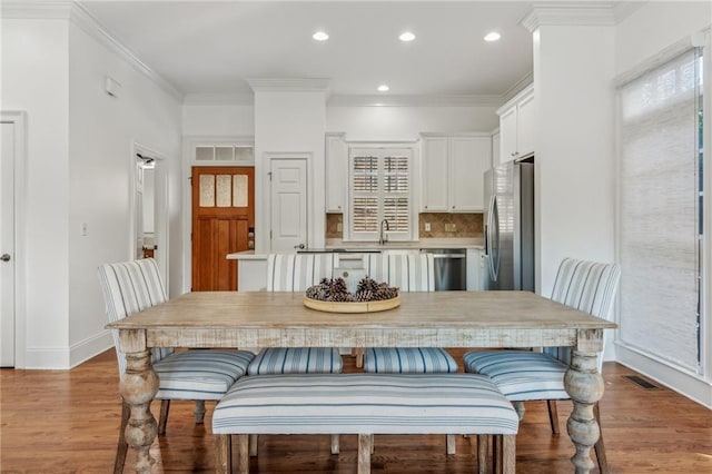 dining area with sink, ornamental molding, and light hardwood / wood-style floors