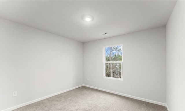 spare room featuring carpet, visible vents, and baseboards