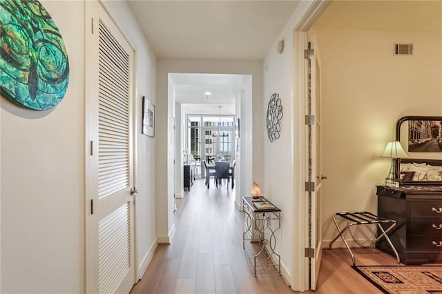 corridor featuring visible vents, light wood-style flooring, and baseboards