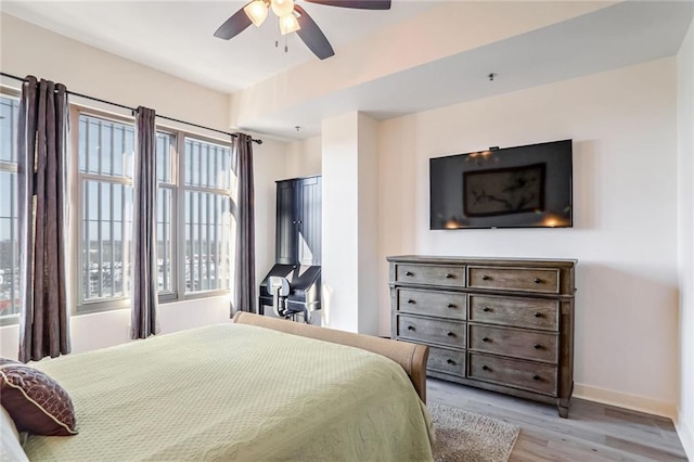 bedroom with light wood-type flooring, baseboards, and a ceiling fan