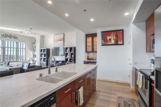 kitchen with light stone countertops, stainless steel appliances, a sink, and open floor plan