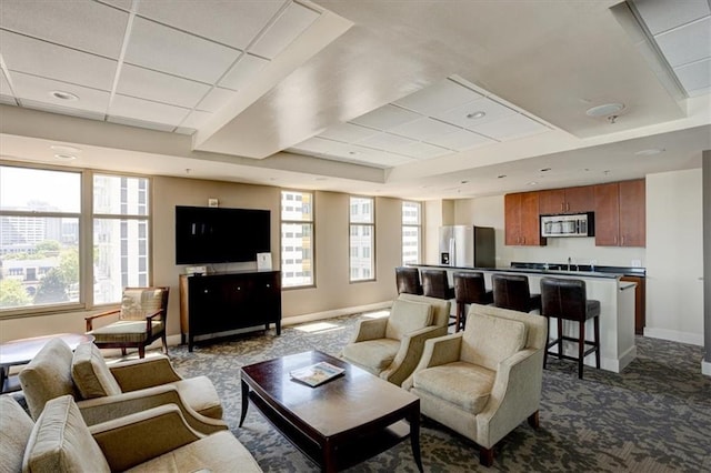 living area featuring a tray ceiling, carpet, a paneled ceiling, and baseboards