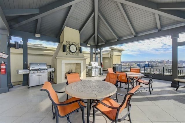 view of patio with a grill, fence, an outdoor fireplace, and a gazebo