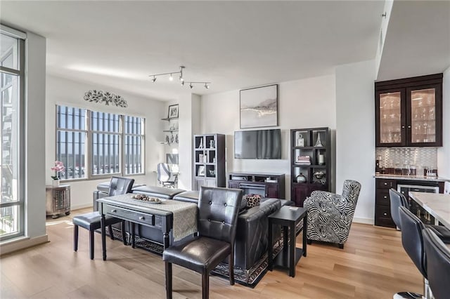 living room with light wood-style floors, baseboards, and a bar