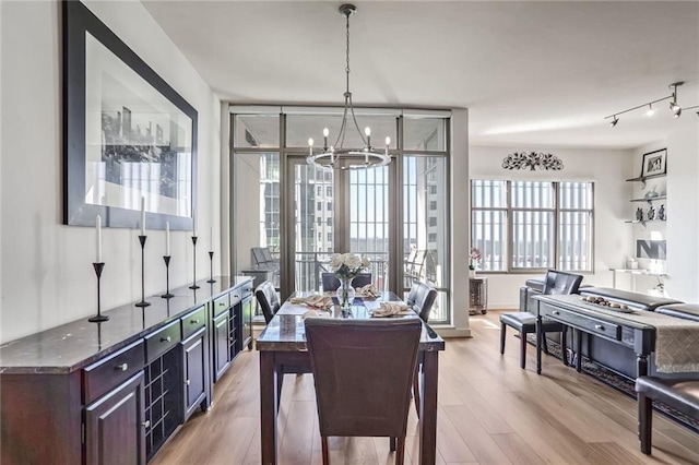 dining space with a chandelier, light wood finished floors, and track lighting