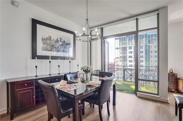 dining space featuring light wood finished floors, baseboards, floor to ceiling windows, and an inviting chandelier