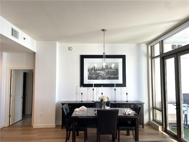 dining area featuring wood finished floors, visible vents, baseboards, expansive windows, and an inviting chandelier