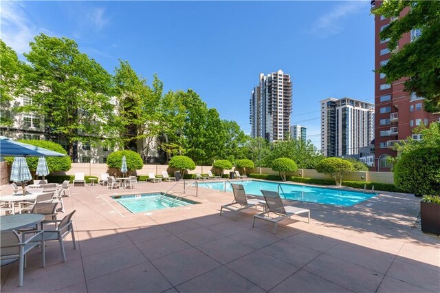 community pool featuring fence, a city view, and a patio area