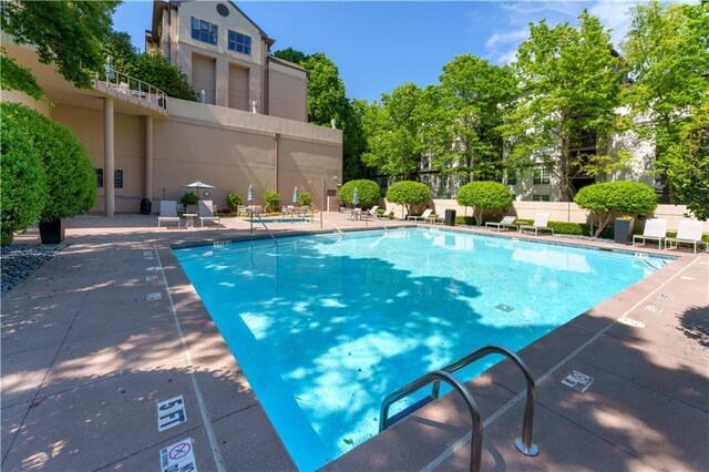 pool with a patio area and fence