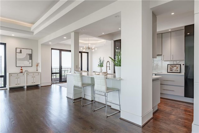 interior space featuring a chandelier, a kitchen breakfast bar, dark wood-style flooring, and modern cabinets