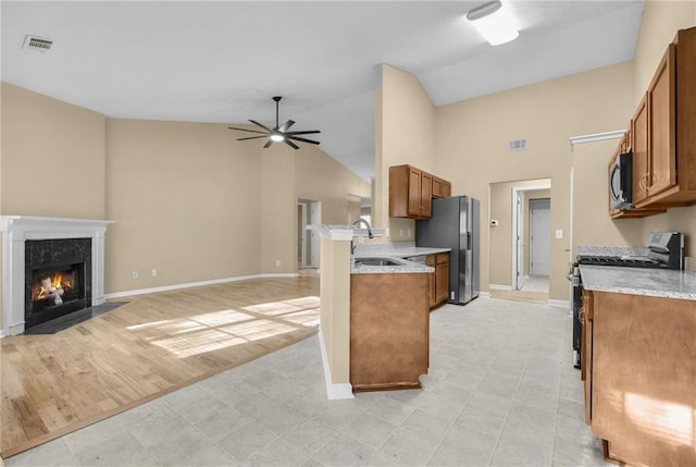 kitchen with stainless steel refrigerator with ice dispenser, a fireplace, sink, light hardwood / wood-style flooring, and black electric range