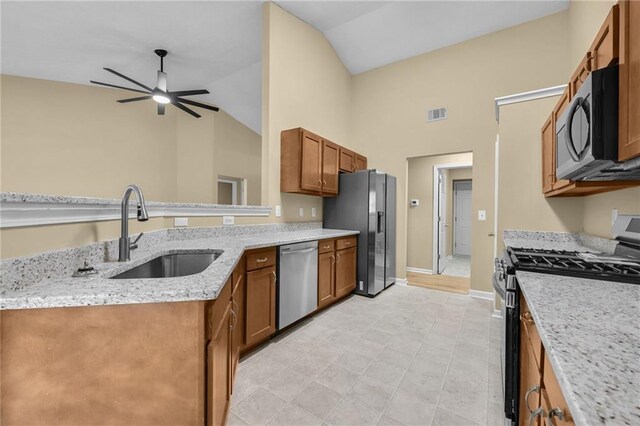 kitchen with lofted ceiling, sink, ceiling fan, light stone countertops, and stainless steel appliances