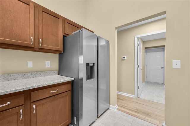 kitchen featuring stainless steel fridge, light stone counters, and light tile patterned floors