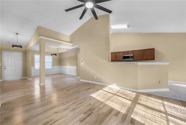 unfurnished living room with ceiling fan, high vaulted ceiling, and light hardwood / wood-style flooring