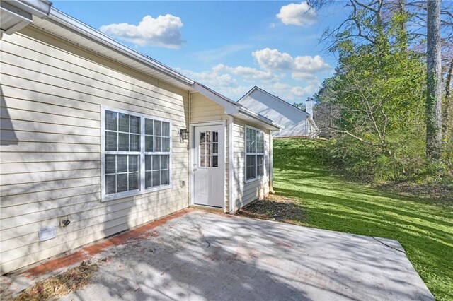 entrance to property featuring a patio area and a yard