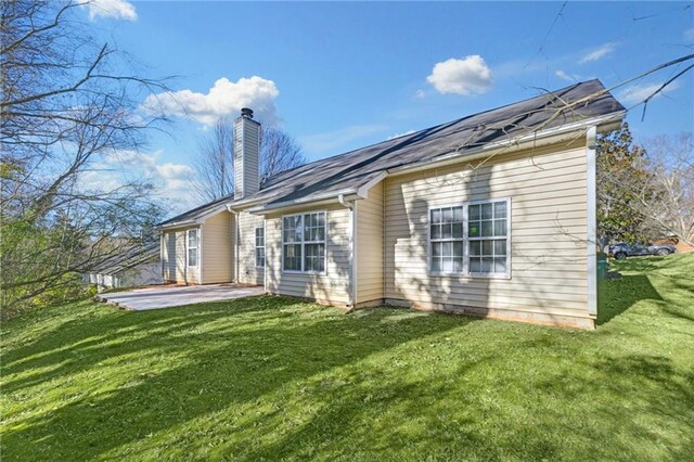 rear view of property with a lawn and a patio