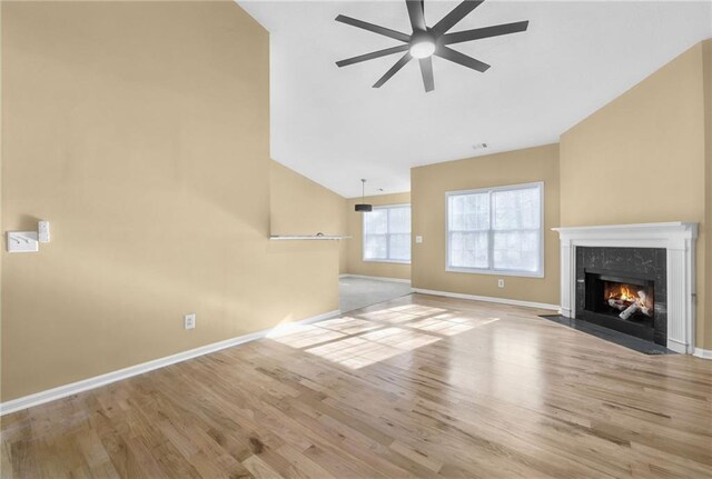 unfurnished living room with a premium fireplace, light hardwood / wood-style flooring, ceiling fan, and vaulted ceiling