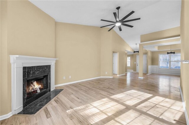 unfurnished living room with ceiling fan, a fireplace, light hardwood / wood-style floors, and lofted ceiling