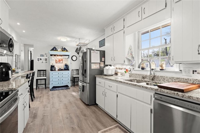 kitchen with a sink, stainless steel appliances, light wood-style floors, and white cabinets