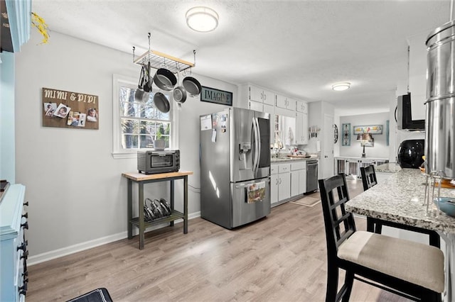 kitchen featuring light wood-style flooring, a textured ceiling, light countertops, and stainless steel refrigerator with ice dispenser