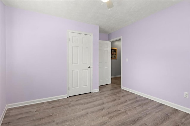 unfurnished bedroom with ceiling fan, baseboards, a textured ceiling, and wood finished floors