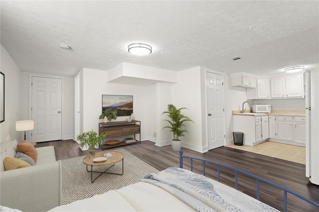 living room featuring visible vents, wood finished floors, baseboards, and a textured ceiling