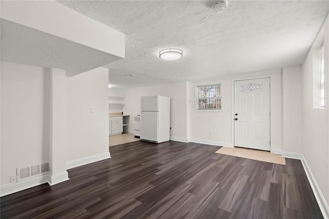 interior space featuring visible vents, baseboards, dark wood finished floors, and freestanding refrigerator