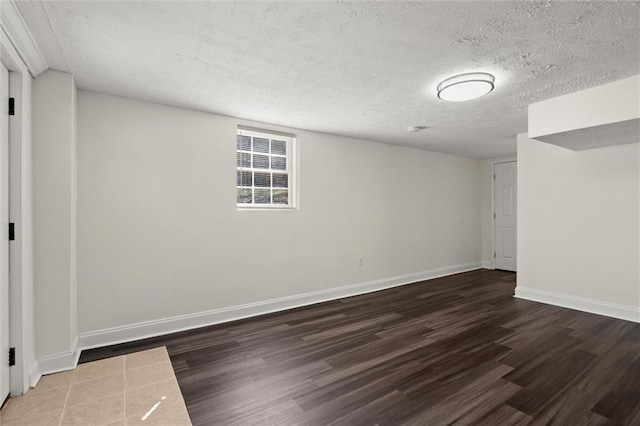 spare room with baseboards, a textured ceiling, and wood finished floors