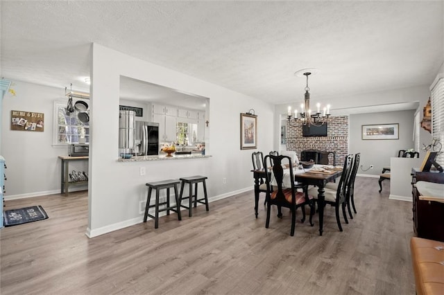 dining space with a textured ceiling, baseboards, and wood finished floors