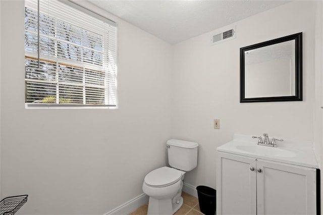 half bathroom featuring vanity, visible vents, baseboards, tile patterned flooring, and toilet