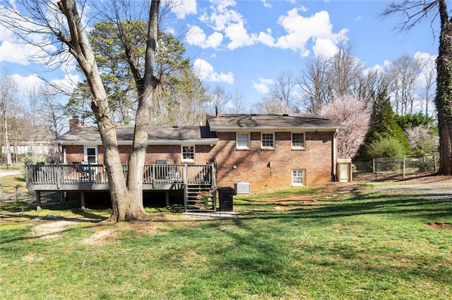 rear view of property with brick siding, fence, a wooden deck, a chimney, and a yard